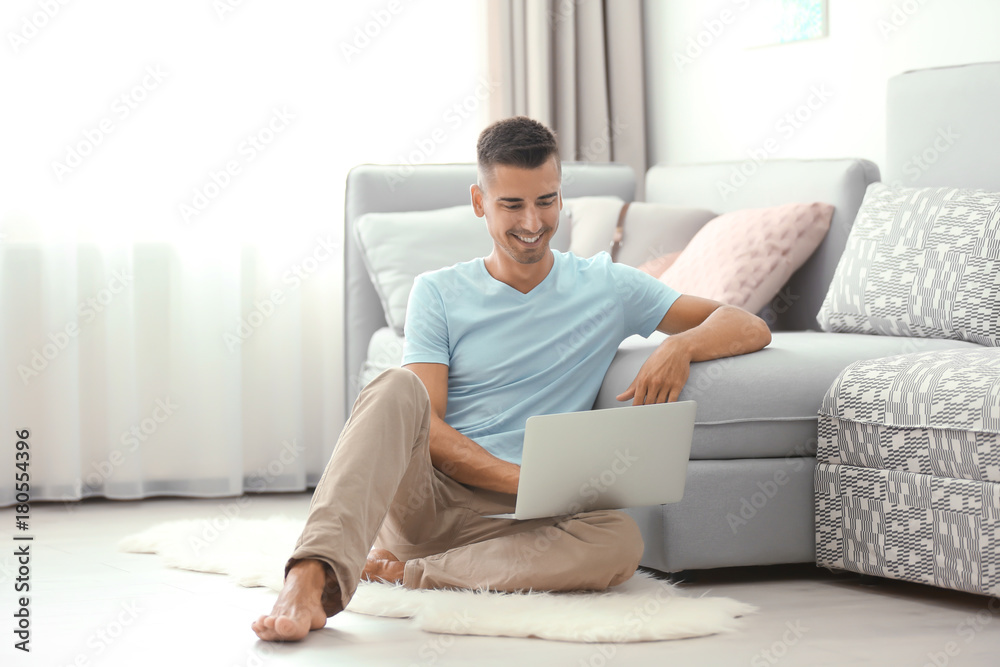 Young man using laptop on floor at home Young man using laptop on floor at home