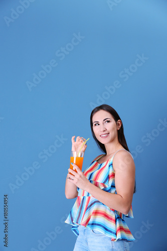 Young woman with glass of orange juice on color background © Africa Studio