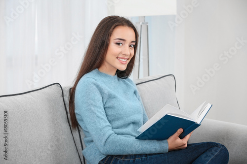 Young woman reading book on...