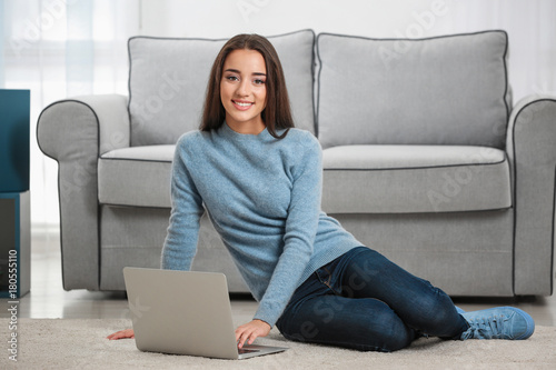 Young woman with modern laptop on carpet at home Free Download Young woman with modern laptop on carpet at home - GFXLoad