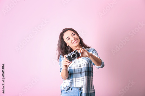 Beautiful female photographer with camera on color background