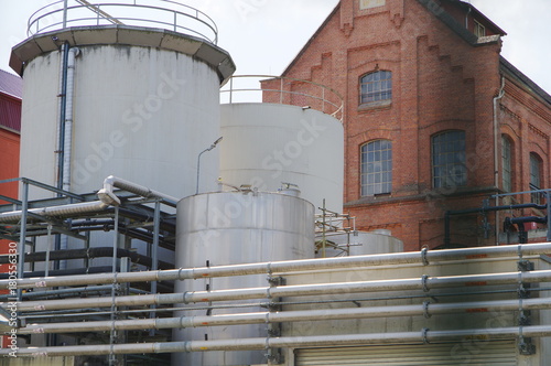 Stahltank neben Industriegebäude aus Backstein