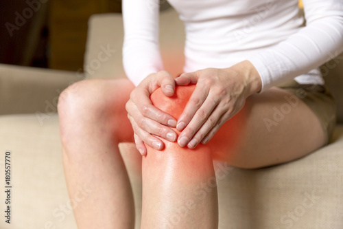 A young woman massaging her painful knee