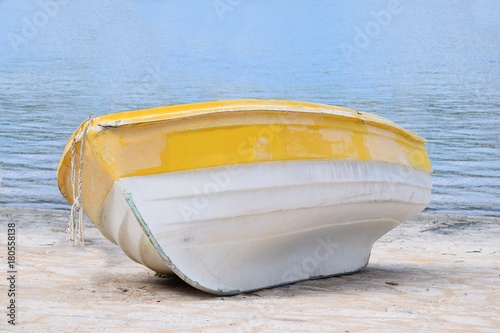 Kleines verlassenes Holzboot liegt am Strand, das Meer mit seichten Wellen im Hintergrund photo