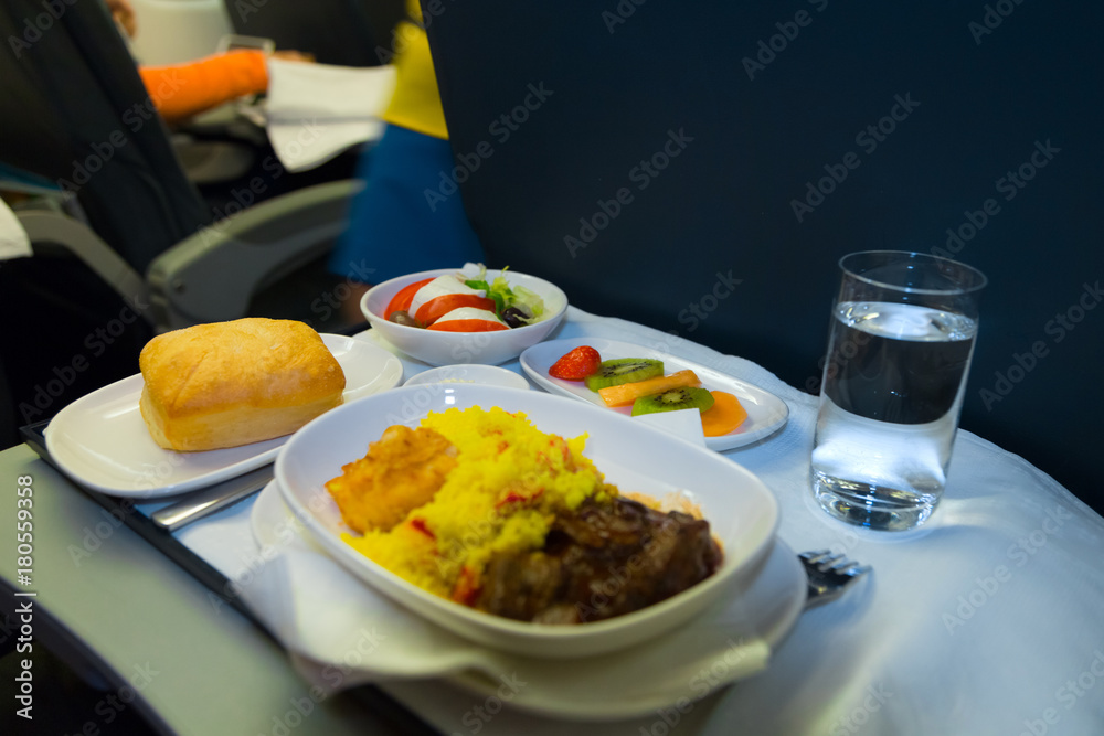 Food served on board of business class airplane on the table. Tray of food in the airplane. Tray of food on the plane, business class travel. Prepared food on the plane Food served on board of business class airplane on the table. Tray of food in the airplane. Tray of food on the plane, business class travel. Prepared food on the plane