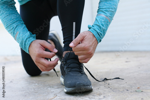 Man tying shoelaces at street before running.