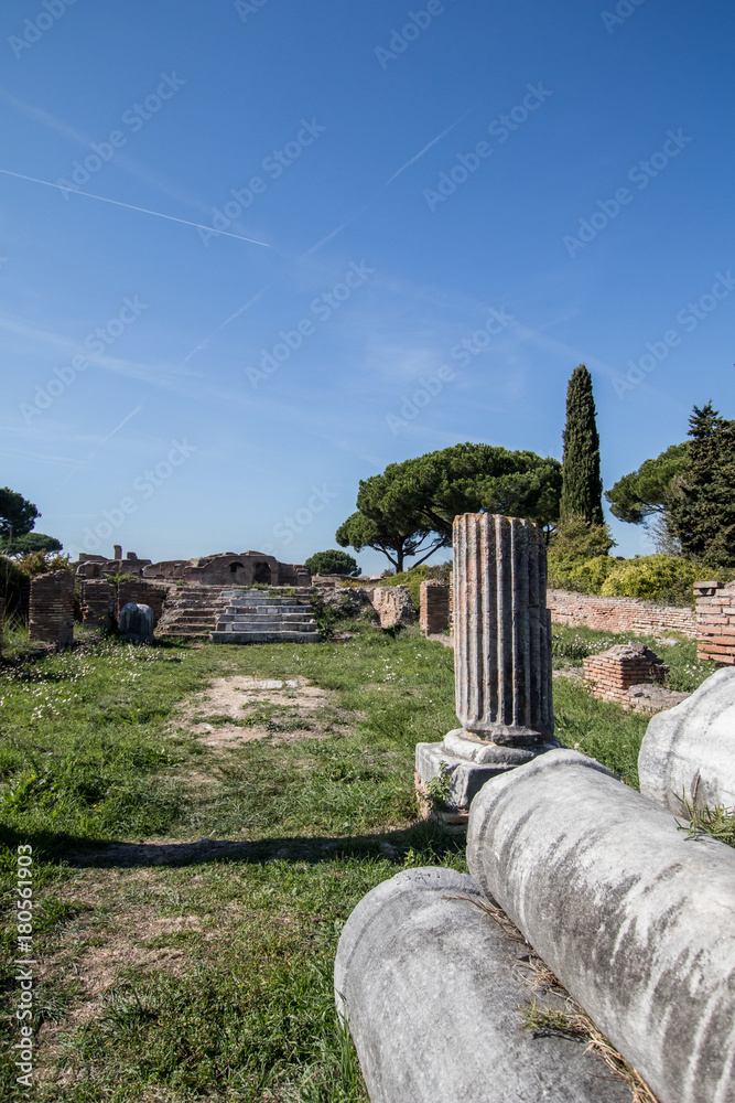 Green field with trees with ancient Roman columns arranged in rows. Old ...