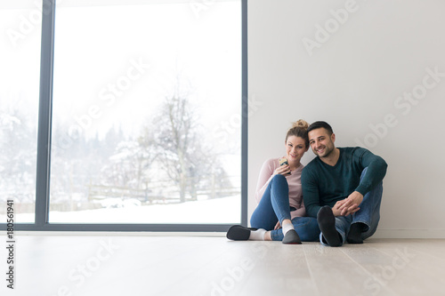 young couple sitting on the floor near window at home