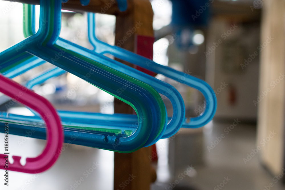 Colored plastic hangers hung on a wooden frame. Small baby hangers in a school