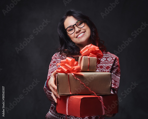 A woman in eyeglasses  holds Christmas gifts. © Fxquadro