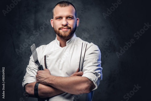 Chef cook holds a knife over dark grey background. photo