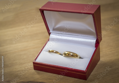 His and Her Gold Wedding rings in a red box on a light brown table