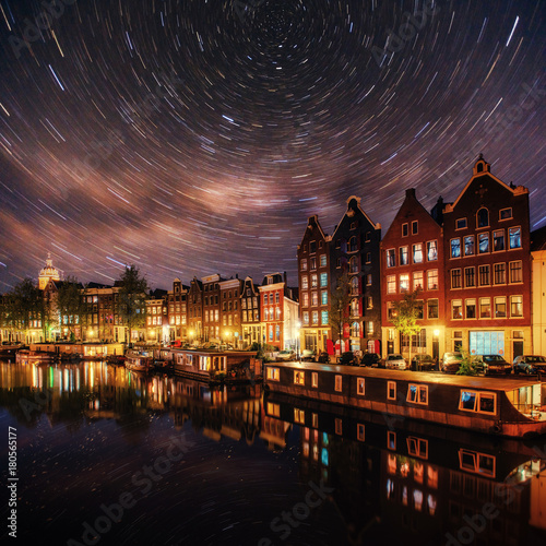 Beautiful night in Amsterdam. Night illumination of buildings and boats near the water in the canal. © standret