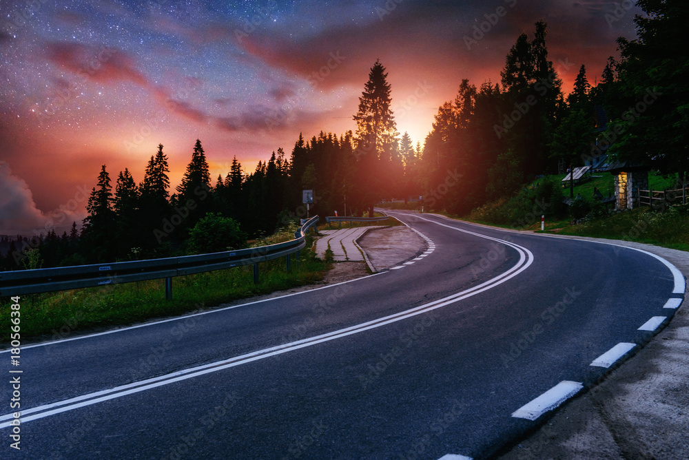 Asphalt road and lonely tree under a starry night sky and the Milky Way ...