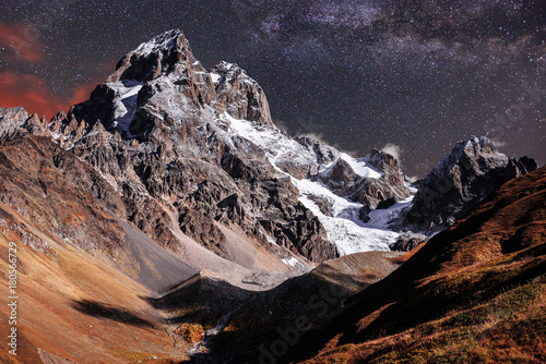 Fantastic starry sky. Autumn landscape and snow-capped peaks. Main Caucasian Ridge. Mountain View from Mount Ushba Meyer, Georgia. Europe photo