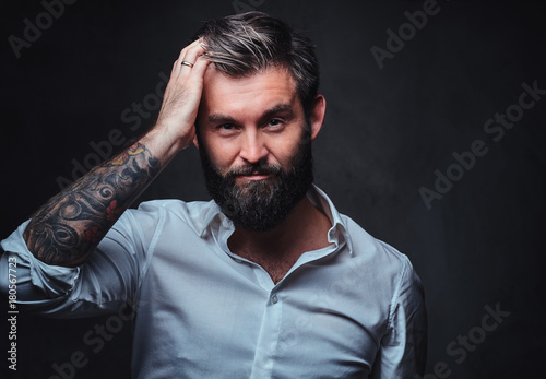 A man with tattoo on arm dressed in a shirt.