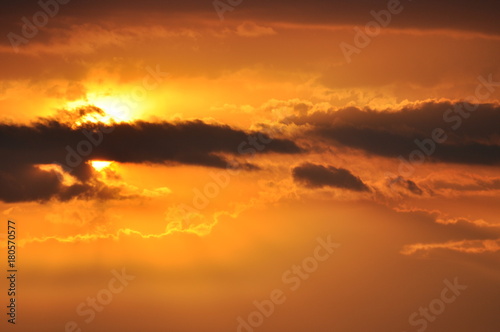 sun hides behind clouds at sunset