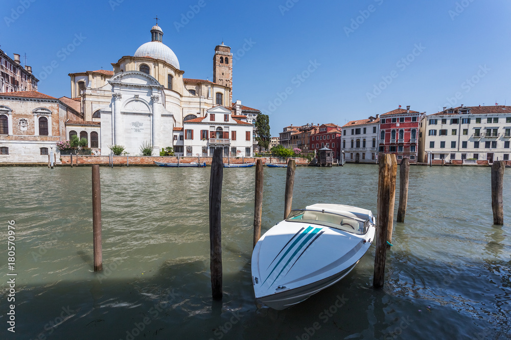 Chiesa di San Geremia and small white motorboat in the harbor in Venice, Italy