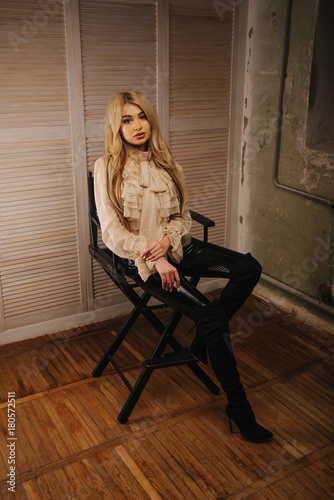 Business style of a sexy blonde at an interview. The girl is ready to give  an interview to the employer. A wooden wall and a grunge room. Dirty job.  Stock Photo
