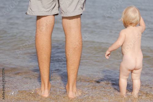 Close up picture of father with one year kid walking on the beach at summertime