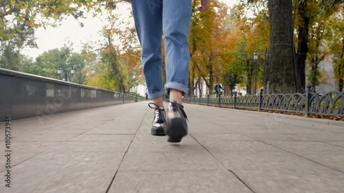 Legs in fashionable platform autumn shoes called creepers. Metallic colour, trendy boots. Woman walking to camera on empty street. Front view. 4k photo
