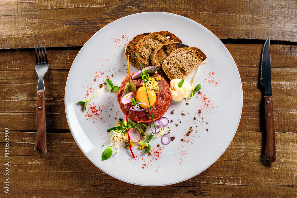 Tasty tartare with toasted bread and salad. Gourmet French meal made of raw ground meat. Delicious healthy food. Top view. Tasty tartare with toasted bread and salad. Gourmet French meal made of raw ground meat. Delicious healthy food. Top view.