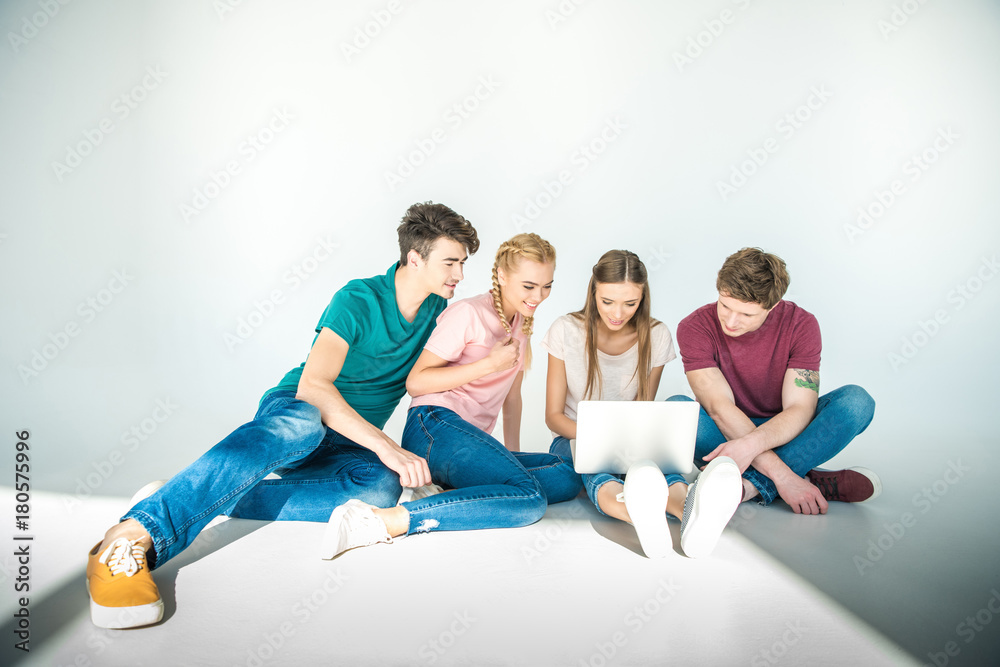 Naklejka premium młodzi przyjaciele za pomocą laptopa