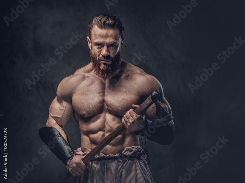 A man holds axe over dark grey background. © Fxquadro