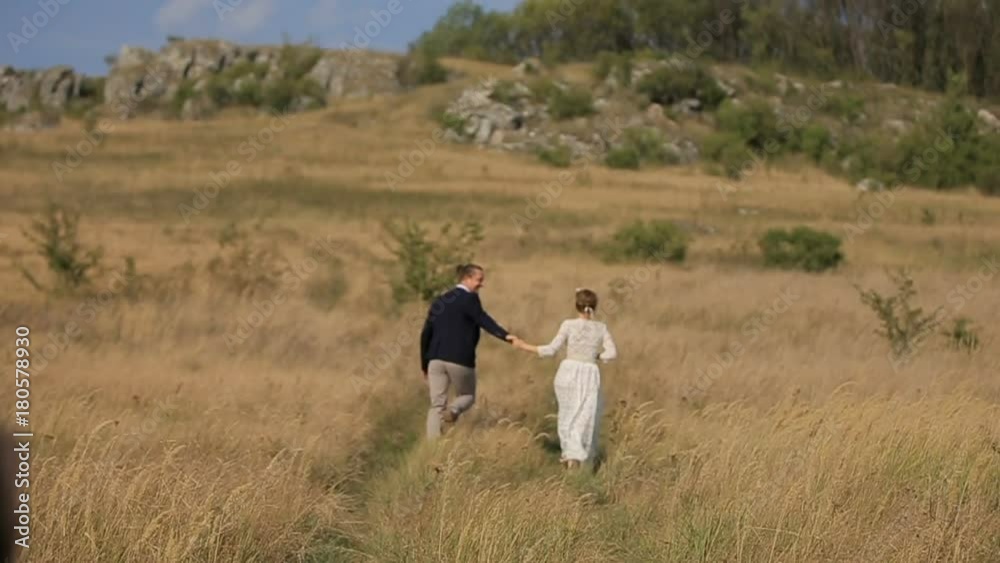 Girl and guy in the field near the cliff. Happy couple having fun outdoors. Happy couple in love in the field. couple running around in the field Girl and guy in the field near the cliff. Happy couple having fun outdoors. Happy couple in love in the field. couple running around in the field