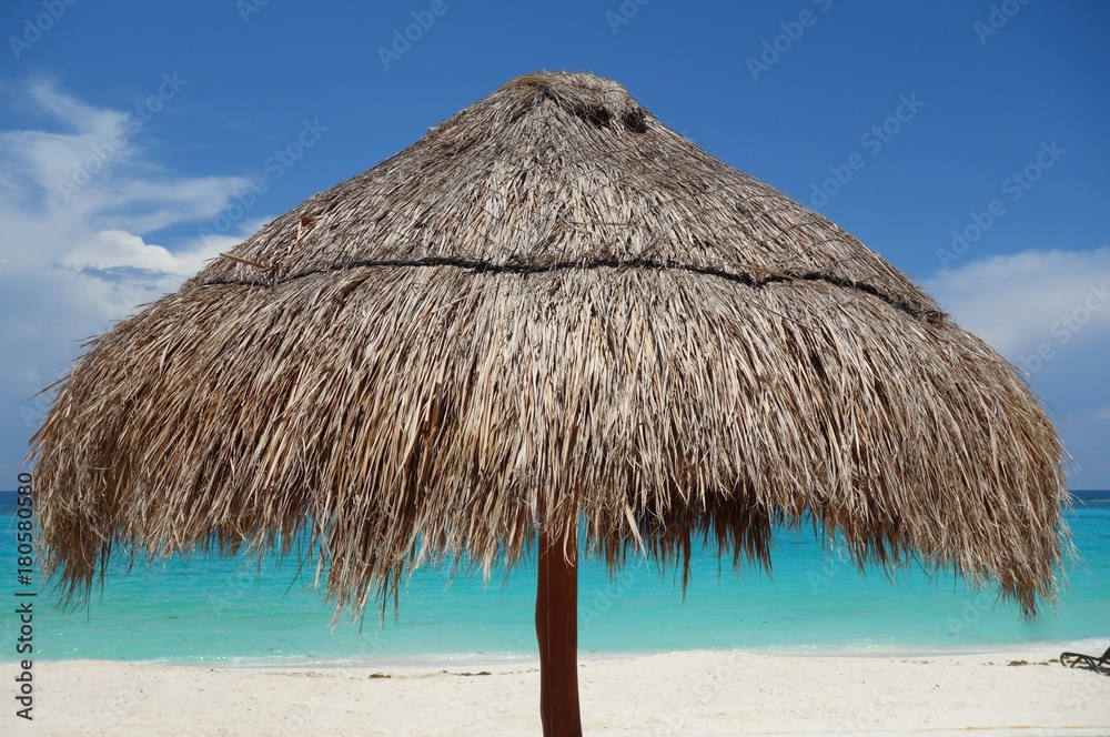 A palapa thatched palm tree sun umbrella on the beach in Cancun, Mexico