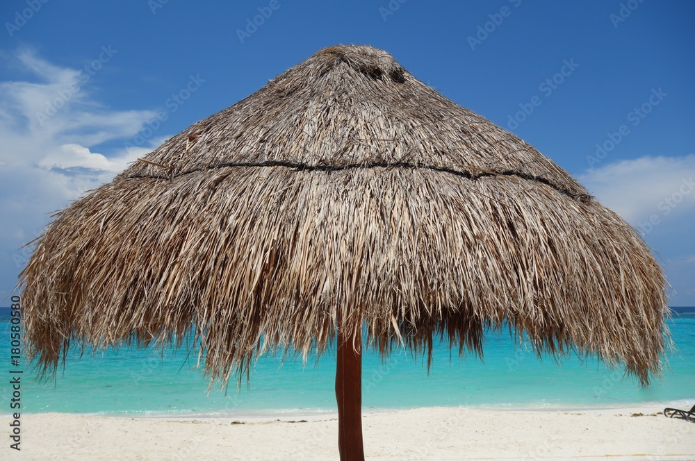 A palapa thatched palm tree sun umbrella on the beach in Cancun, Mexico A palapa thatched palm tree sun umbrella on the beach in Cancun, Mexico