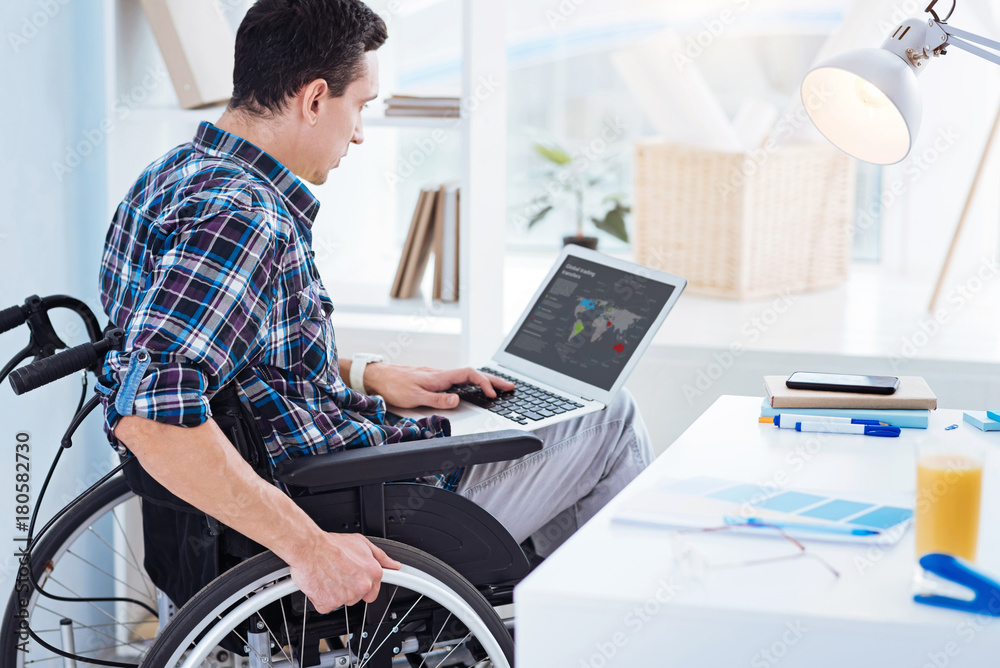 Being attentive. Concentrated brunette holding laptop on knees and sitting in semi position while looking at computer screen Being attentive. Concentrated brunette holding laptop on knees and sitting in semi position while looking at computer screen