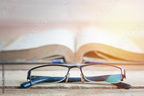 Education, improve and knowledge concept, glasses and book on wood table .