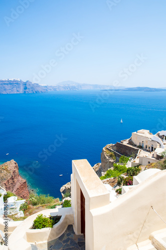 View of Fira town - Santorini island,Crete,Greece. White concrete staircases leading down to beautiful bay with clear blue sky and sea © vitmark