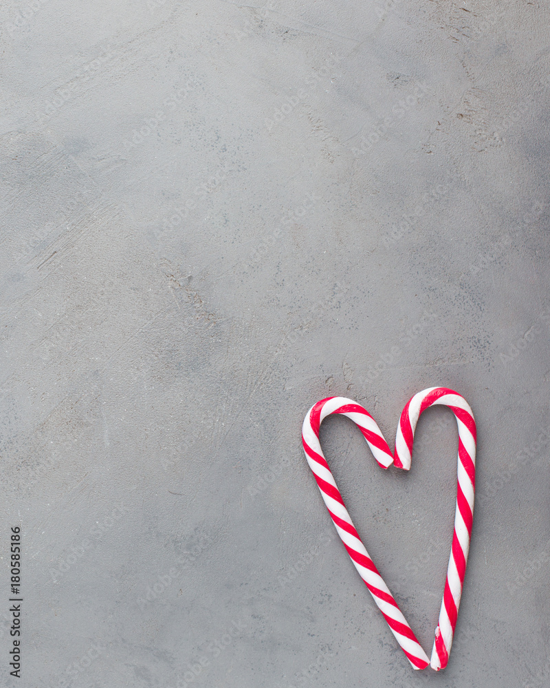 Heart of two red-white candy canes on the gray concrete background. Beautiful background. Flat lay, top view Heart of two red-white candy canes on the gray concrete background. Beautiful background. Flat lay, top view