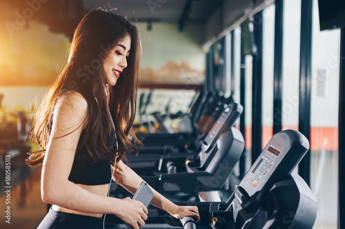 Asian woman exercising in the gym, Young woman workout in fitness for her healthy and office girl lifestyle. She listening the music while exercising.