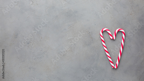Heart of two red-white candy canes on the gray concrete background. Beautiful background. Flat lay, top view