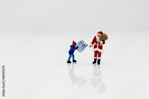 Miniature people: Santa Claus and children with gift.