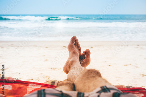 Mans feet men relaxing on the beach on a deckchair.