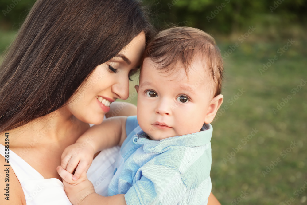Beautiful young mother holding cute baby boy, outdoors Beautiful young mother holding cute baby boy, outdoors
