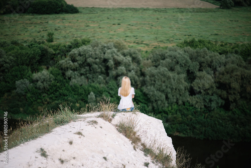 Bild auf Leinwand Young beautiful blonde woman sitting back to the camera on top of the white chal