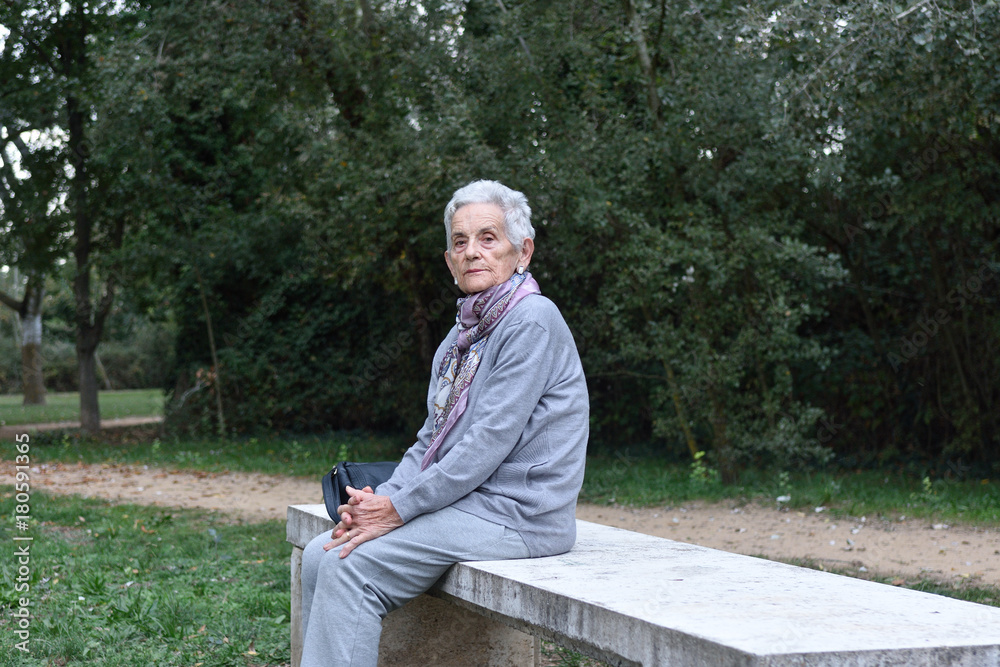 Fototapeta premium senior woman sitting alone on a bench in a park