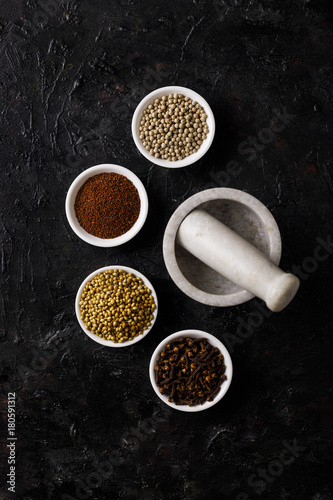 Indian Spices on a Black Background. With A White Mortar And Pestle.