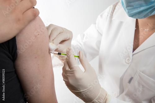Close up of a female doctor or nurse giving an injection or vaccine to a male patient