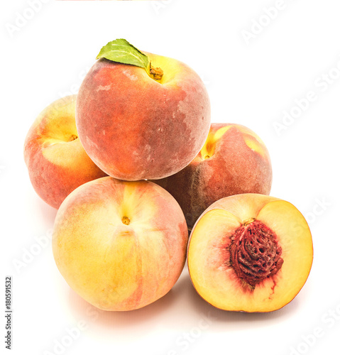 Folded peaches, one with green leaf and one sliced half with a stone, isolated on white background.