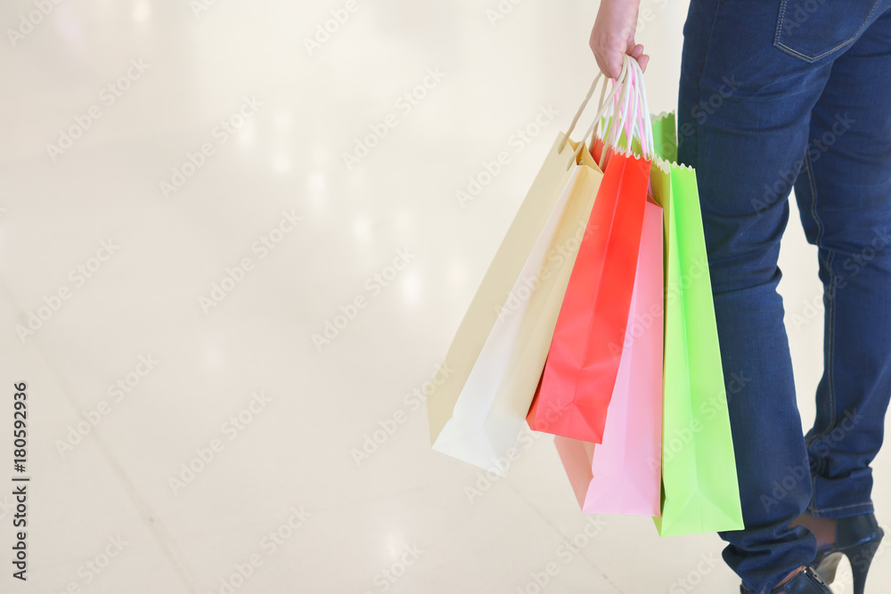 Close up of woman customer leg with colorful paper shopping bags.