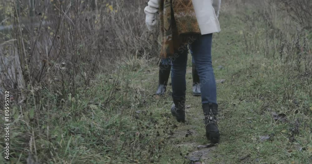 pretty smiling girl walking towards her friend / sister in the forest. Two girls / women meeting each other in the park or forest or trail and hug. Hiking outdoor or chilling on nature