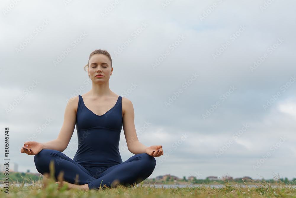 Young attractive girl practicing yoga, sitting in Half Lotus exercise, Ardha Padmasana pose. Young attractive girl practicing yoga, sitting in Half Lotus exercise, Ardha Padmasana pose.