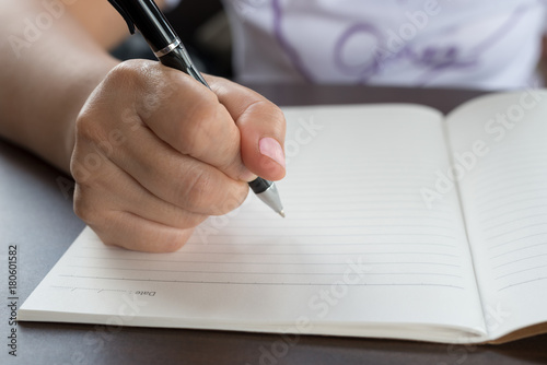Closeup of woman's hand writing on paper book