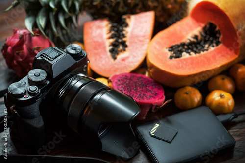 Tropical fruit near modern laptop and photocamera on wooden background. Tools for photo blogger anr travel journalist. Up view photo